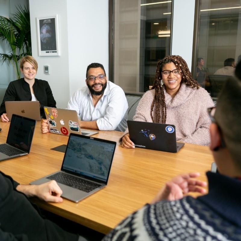 People meeting around a board room table using laptops